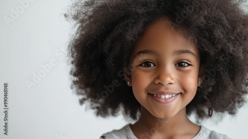 African American girl with an afro, smiling against a white background. 