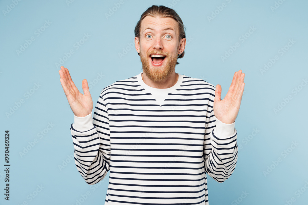 Naklejka premium Young shocked surprised overjoyed happy man he wear striped sweatshirt casual clothes look camera spread hands isolated on plain pastel light blue cyan background studio portrait. Lifestyle concept.