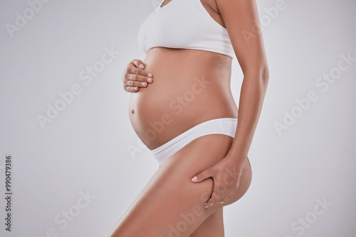 Stomach, wellness and pregnant woman in studio with skincare, growth and body development in maternity. Pregnancy, shape and girl with self care for stretch marks, healthy skin and white background