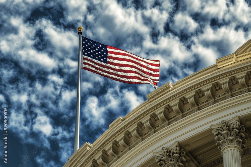 Fototapeta premium American flag waving on a flagpole atop a historic government building with a dramatic cloudy sky. Patriotic symbol and national pride. Design for Independence Day, Memorial Day, or political events