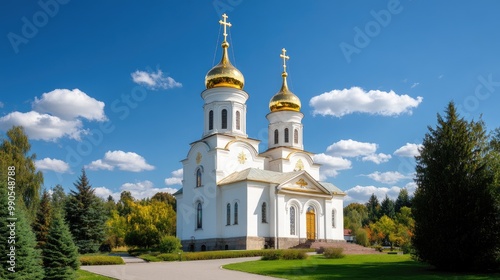 A breathtaking view of Nikolai Orthodox Church with golden domes under a clear blue sky, surrounded by lush greenery and vibrant flowers
