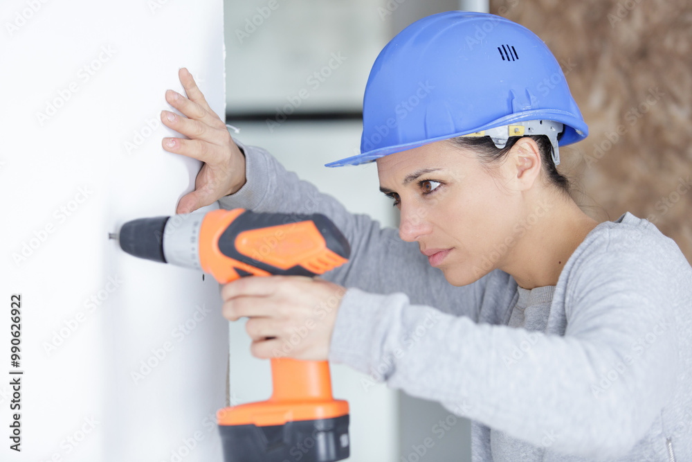 female carpenter at work using hand drilling machine