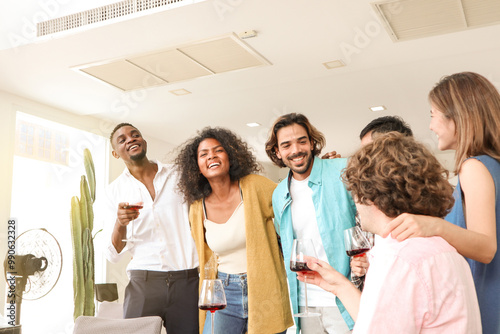Joyful multi-racial friends having a conversation and laughing together at a dining table, smiling as they enjoy champagne in a warm and loving toast, sharing a moment of togetherness and celebration.