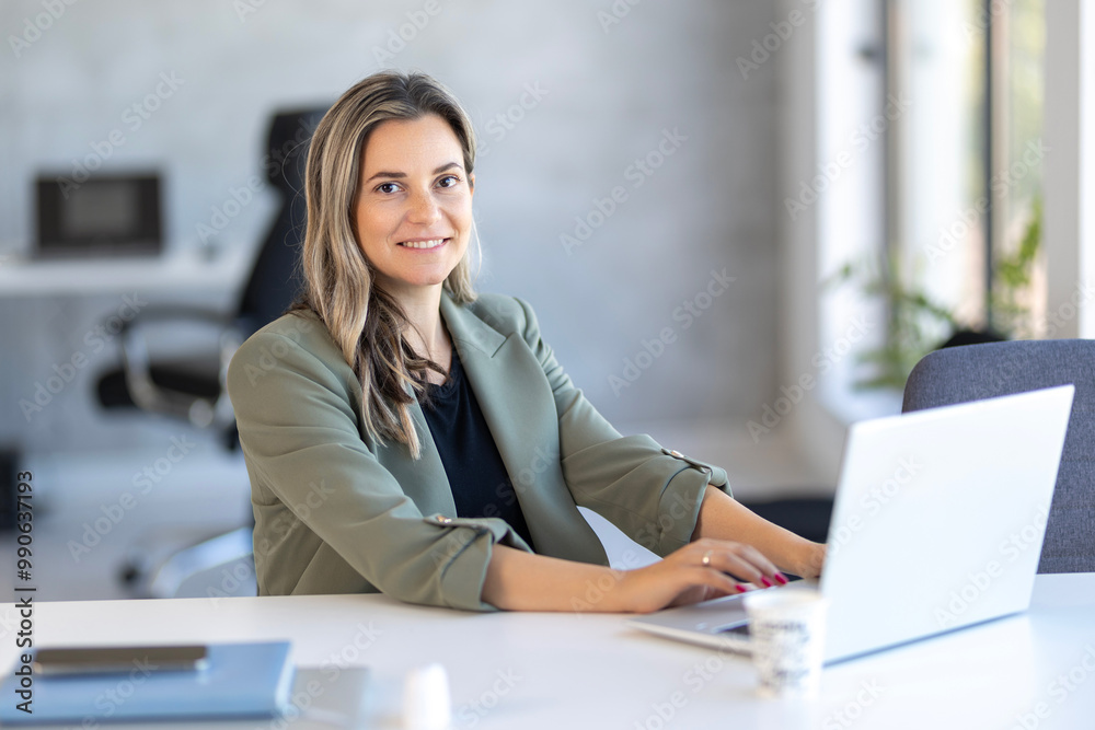Beautiful business woman smiling while working on laptop, looking at camera position Beautiful business woman smiling while working on laptop, looking at camera position