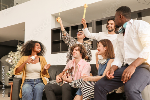 A group of multiracial teenagers is playing guitar and singing a song together while happily having fun blowing bubbles at the afternoon party. Recreational activity and celebration concepts.