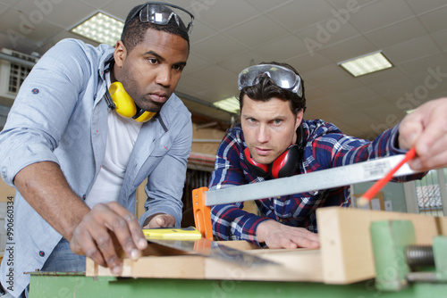 Photos carpenter teaching apprentice how to measure wood