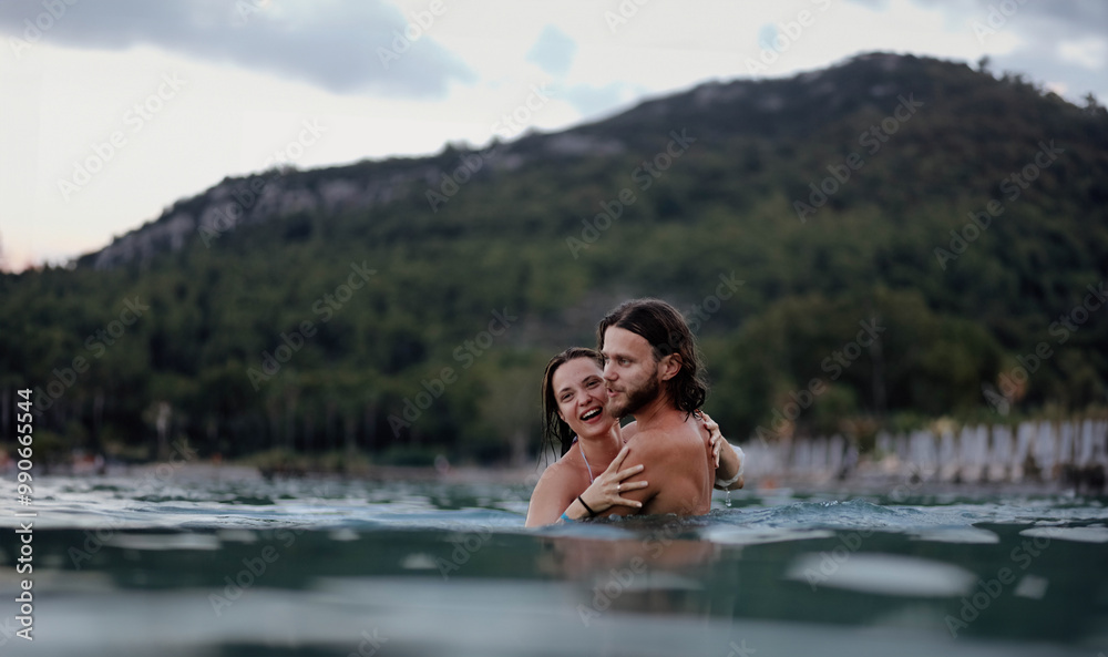 Fototapeta premium couple in love in water swim in the sea in the evening and love each other, long-haired couple.