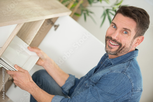 man reaching tidy plate in kitchen cabinet photo