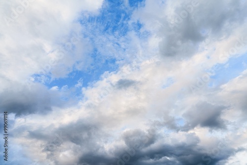 A beautiful and dramatic blue sky filled with a captivating mix of bright white clouds and ominous dark storm clouds. This image is perfect for any weather or nature-themed project, evoking a sense of