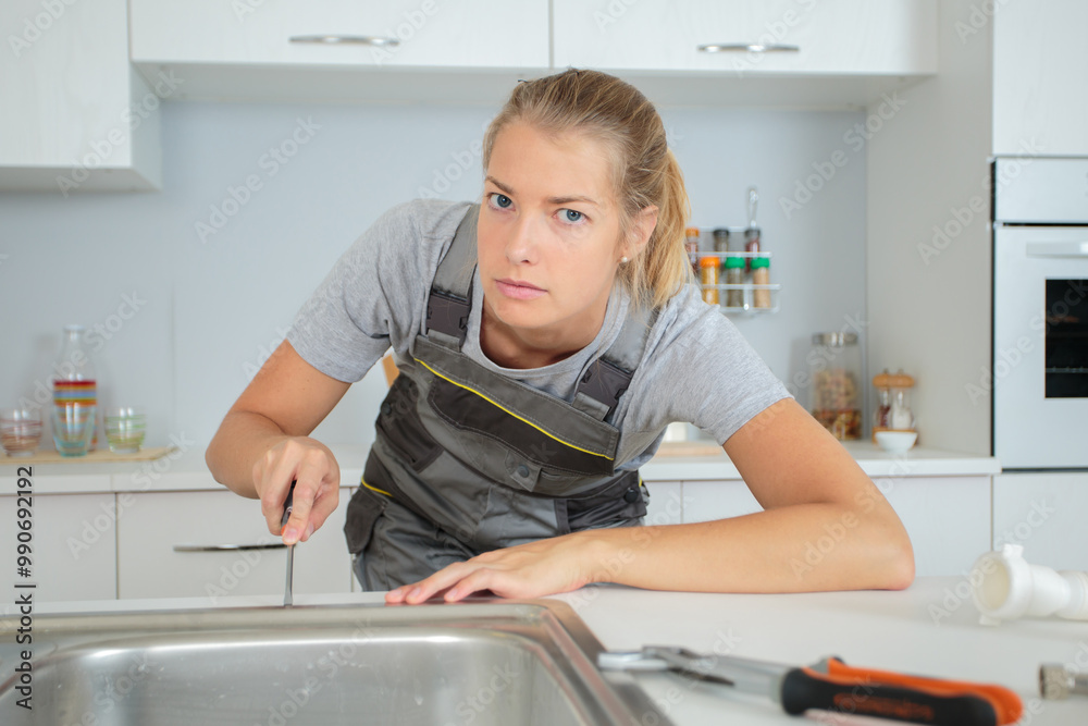 worried woman plumber unscrewing the sink screws worried woman plumber unscrewing the sink screws