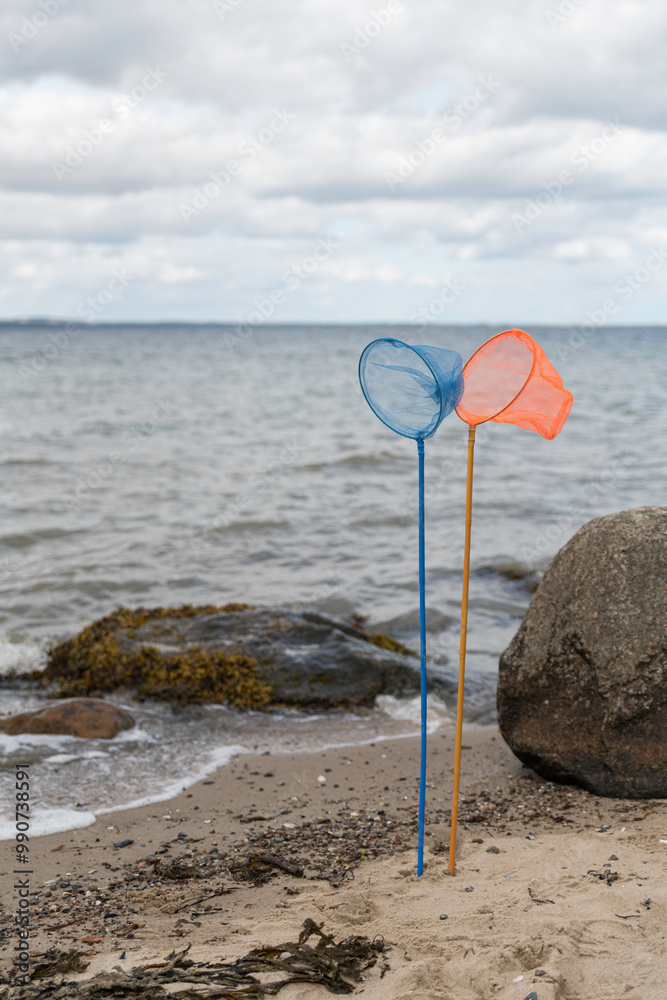 an orange and a blue fishing net on a pole standing on the beach an orange and a blue fishing net on a pole standing on the beach