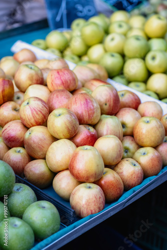 Brightly colored apples are stacked enticingly at a lively market, showcasing a variety of green and red shades, perfect for autumn gatherings and culinary delights.