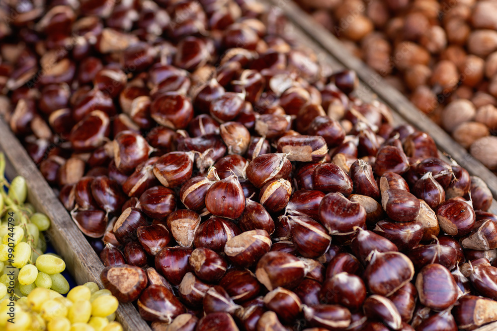 A close-up of freshly gathered chestnuts showcases their glossy shells, glimmering in the warm autumn light at a vibrant market stall filled with seasonal produce. A close-up of freshly gathered chestnuts showcases their glossy shells, glimmering in the warm autumn light at a vibrant market stall filled with seasonal produce.