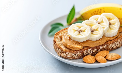 Delicious toast with peanut butter, banana slices, and almonds on a white plate.