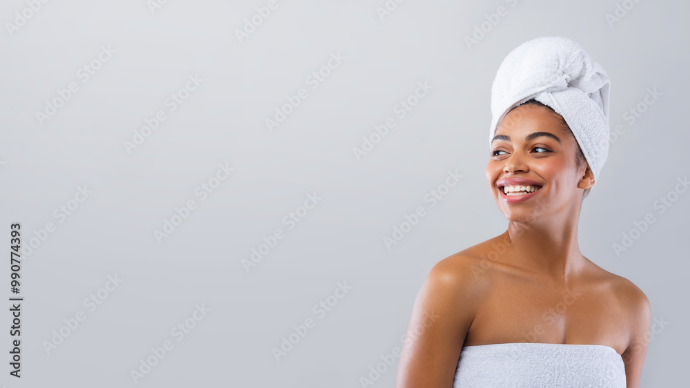 Happy young african woman wrapped in white bath towels after shower looking at empty space, grey studio background, discounts at spa hotel Happy young african woman wrapped in white bath towels after shower looking at empty space, grey studio background, discounts at spa hotel
