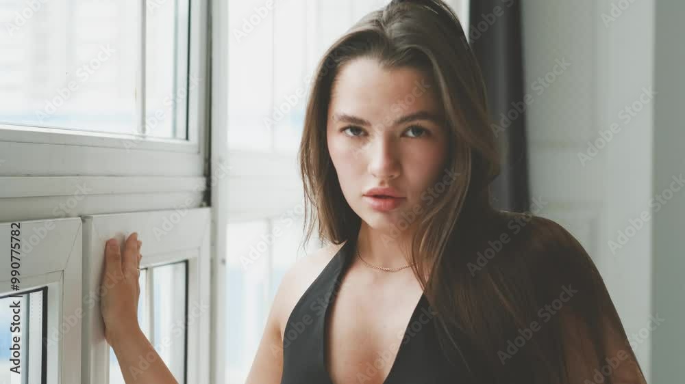 Portrait of young beautiful model posing in black lingerie and stockings near a large window. Calm cute brunette in fashionable lingerie. Portrait of young beautiful model posing in black lingerie and stockings near a large window. Calm cute brunette in fashionable lingerie.