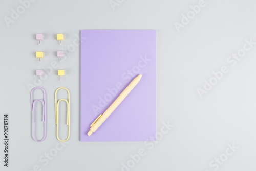 Top view of purple notebook on grey background. Paperclips, pen and pins. School, office wallpaper. Flat lay, copy space.