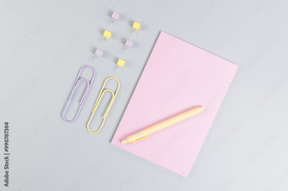 Top view of pink notebook on grey background. Paperclips, pen and pins. School, office wallpaper. Flat lay, copy space.