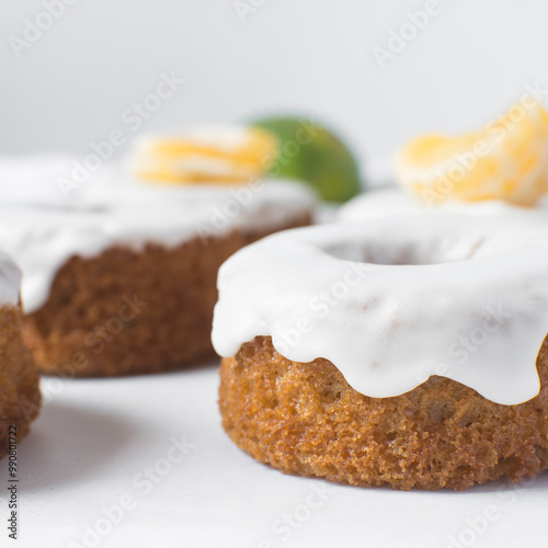 Iced mini bundt cake on a white tray, vanilla bundlette cakeswith a clementine segment on a white background, small vanilla bundt cakes with an icing glaze photo