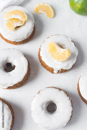 Iced mini bundt cake on a white tray, vanilla bundlette cakeswith a clementine segment on a white background, small vanilla bundt cakes with an icing glaze photo