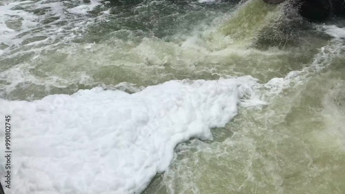 Shapes and textures of white and brown river waste foam. Footage of a dirty river affected by factory waste. River is dirty due to water pollution. 4k video of pollution background.