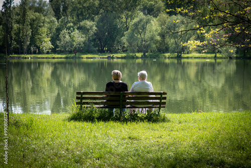 фотографія Two elderly women sit by the lake and admire the nature