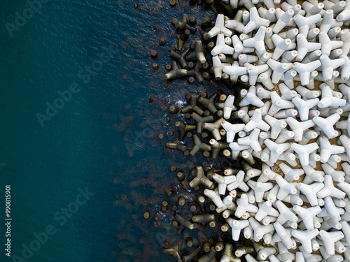 Murais de parede Heavy concrete tetrapods lined along the shoreline at a coastal area during dayl