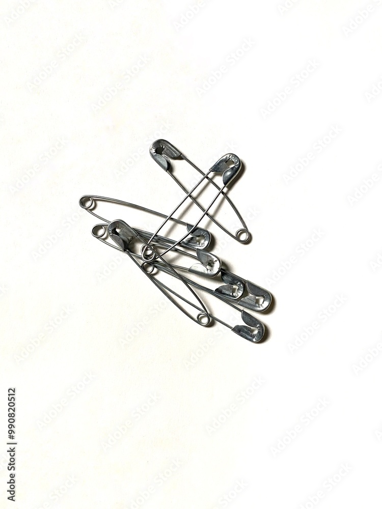Fototapeta premium Silver metal safety pins isolated on white background. Used for fashion, hobby, crafts, or household.