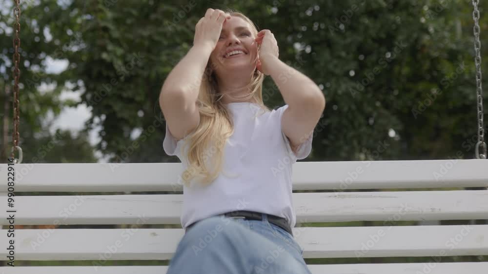 Cheerful and Relaxed Blonde Woman Swinging in the Park, Radiating Joy Cheerful and Relaxed Blonde Woman Swinging in the Park, Radiating Joy