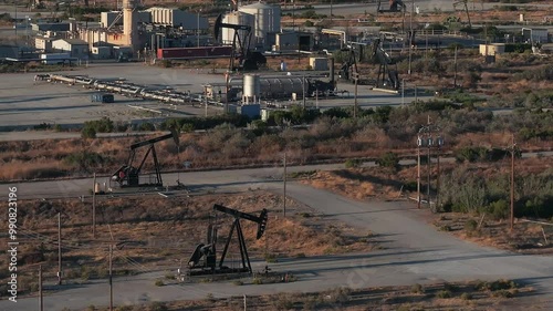 Aerial view of the oil rigs and wells in the Midway-Sunset shale oil fields, the largest in California. A pumpjack operates at an oil field. Oil pump rig energy industrial machine for petroleum.