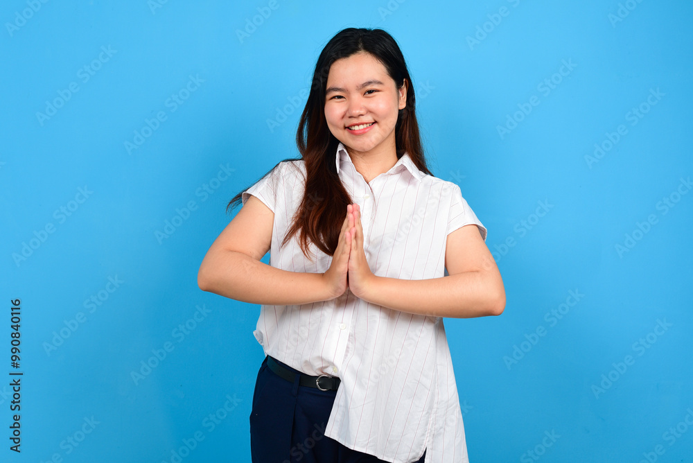 Smiling young Asian woman waving hand greeting isolated over blue background Smiling young Asian woman waving hand greeting isolated over blue background