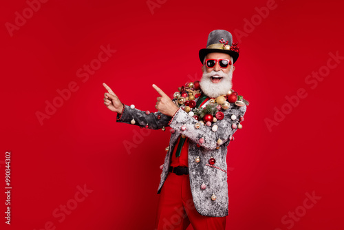 Photo of nice aged elegant man point empty space wear christmas tree balls costume sunglasses isolated red color background photo