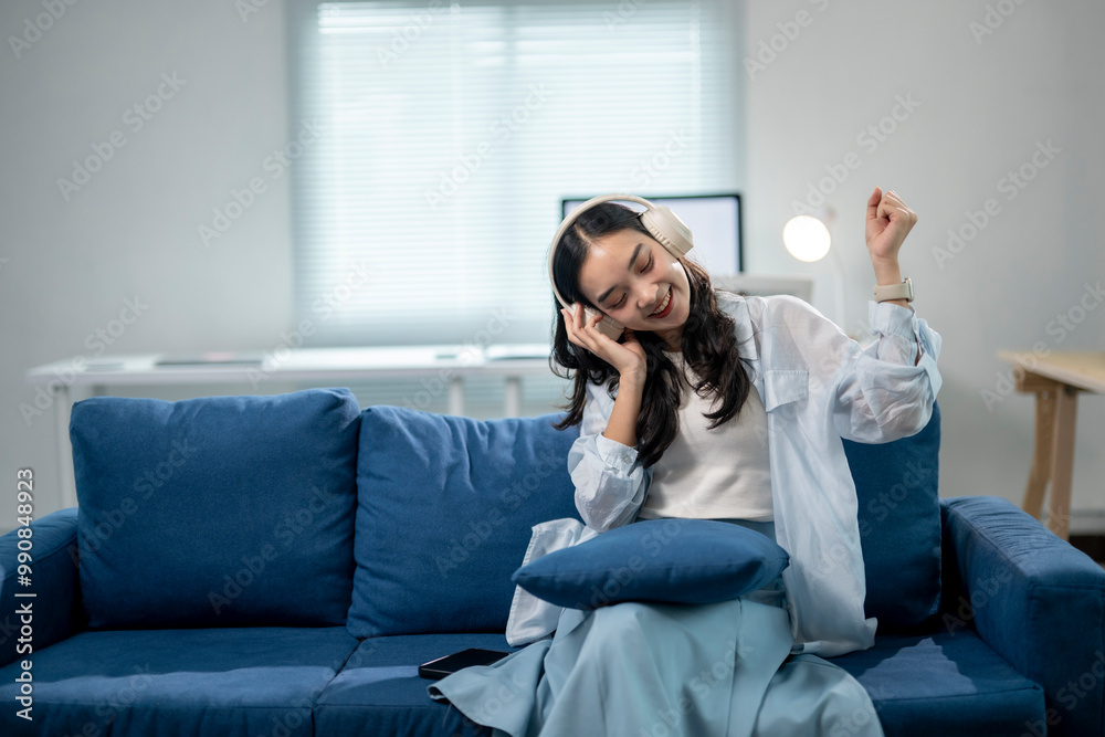 A woman is sitting on a blue couch and listening to music A woman is sitting on a blue couch and listening to music