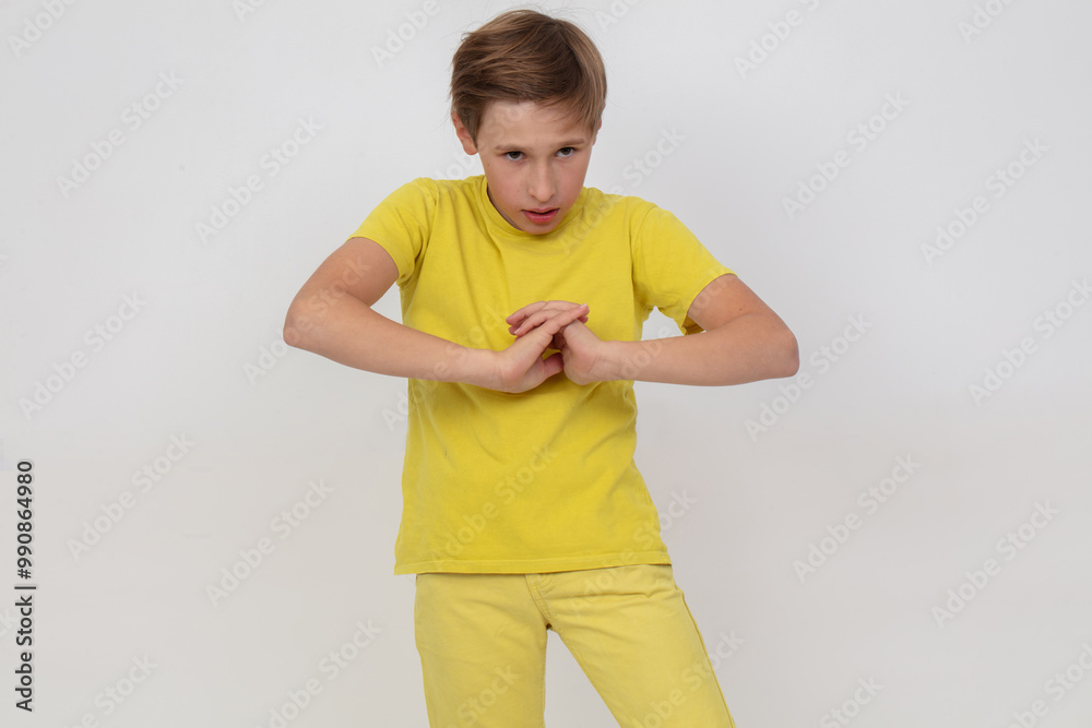 A young guy in a yellow shirt stands with his arms crossed and looks at the camera. He is in a serious or thoughtful mood. A young guy in a yellow shirt stands with his arms crossed and looks at the camera. He is in a serious or thoughtful mood.