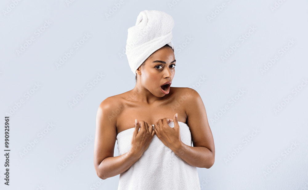 Amazing spa deal. Black woman wrapped in towels expressing shocking emotions, grey background Amazing spa deal. Black woman wrapped in towels expressing shocking emotions, grey background