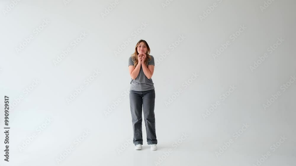 Satisfied and joyful Caucasian young adult woman standing with crossed finger in hope on white background. Desire or wish gesture.