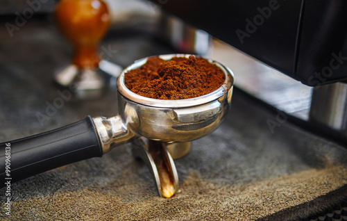 Close-up of ground coffee in portafilter or portable coffee filter handle and ground coffee for a coffee making machine on coffee shop photo