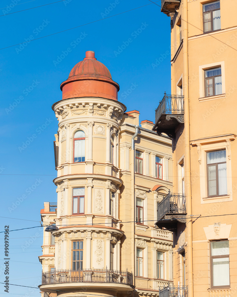 Fototapeta premium Close-up of a historic residential building with a tower and ornate facade in sunlight. Architectural details of a European city.