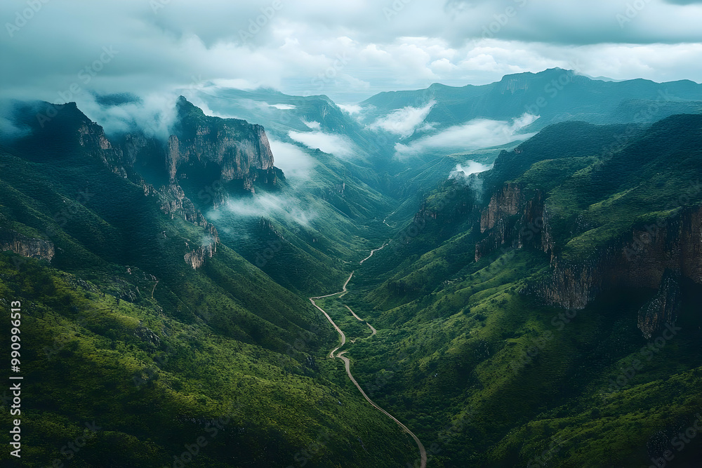 Naklejka premium Winding Road Winds Through Lush Green Valley in Mountain Range with Fog