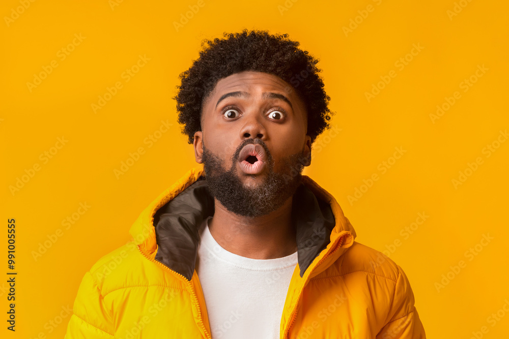 Young emotional surprised bearded man standing with open mouth over orange background, winter set Young emotional surprised bearded man standing with open mouth over orange background, winter set