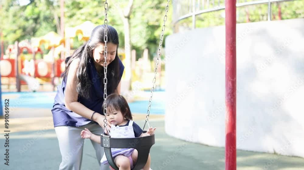 Chinese Malaysian parents in their 30s and 1-year-old daughter playing happily on swings and seesaws in KLCC Park on June morning in Kuala Lumpur, Malaysia, filmed as horizontal slow motion video. Chinese Malaysian parents in their 30s and 1-year-old daughter playing happily on swings and seesaws in KLCC Park on June morning in Kuala Lumpur, Malaysia, filmed as horizontal slow motion video.