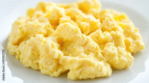 A close-up of perfectly cooked scrambled eggs, with a smooth texture, placed on a clean white background, ideal for a healthy breakfast concept.