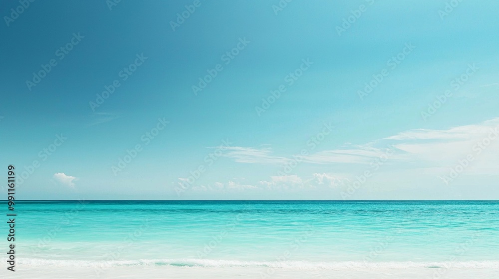 Turquoise blue ocean water with small waves crashing on a white sand beach and a bright blue sky with a few fluffy white clouds Turquoise blue ocean water with small waves crashing on a white sand beach and a bright blue sky with a few fluffy white clouds