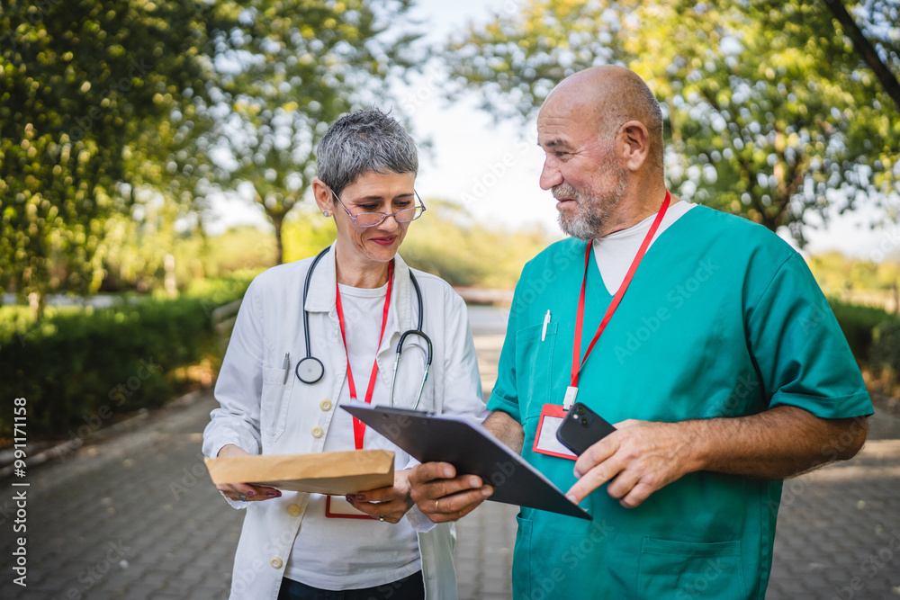 Healthcare professionals colleagues discuss patient records outdoors Healthcare professionals colleagues discuss patient records outdoors