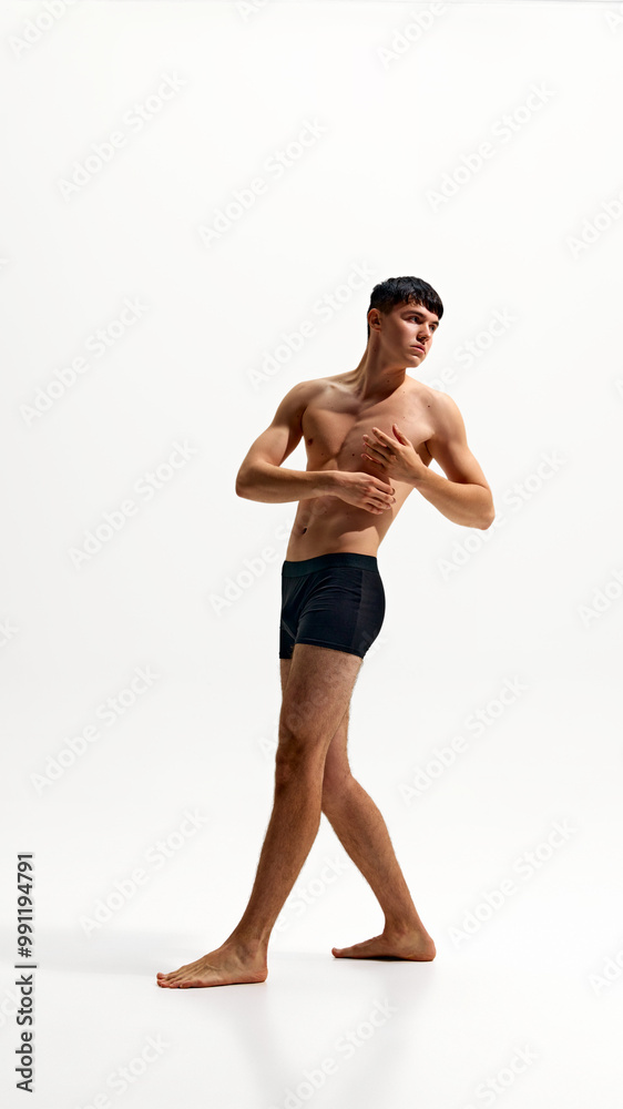 Full-length portrait of handsome young man with relief, muscular body, posing in black boxers isolated on white studio background. Concept of male beauty, body and skin care, health, sport Full-length portrait of handsome young man with relief, muscular body, posing in black boxers isolated on white studio background. Concept of male beauty, body and skin care, health, sport