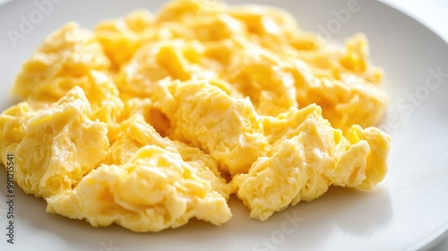 A portion of soft, buttery scrambled eggs on a white surface, highlighting the texture and warmth of this simple dish.