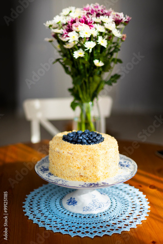 Homemade birthday cake called Apfelmus decorated with blueberries on porcelain plate on blue lace napkin