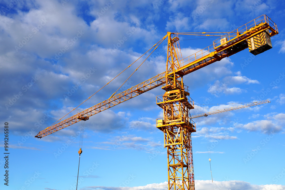Construction crane on on blue sky background. Tower Crane on building construction. Multi Storey Residential Building under construction. Tower Crane close up. Construction crane on on blue sky background. Tower Crane on building construction. Multi Storey Residential Building under construction. Tower Crane close up.