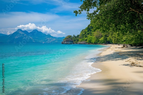 A beautiful beach with a blue ocean and a mountain in the background. The beach is empty and the water is calm