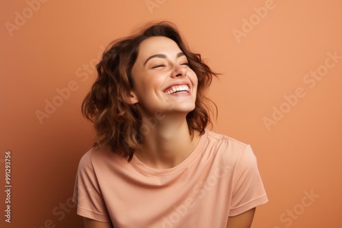 Portrait of a joyful woman in her 20s dressed in a casual t-shirt over soft brown background